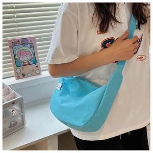 Detail of light blue dumpling bag with a cute white puppy plush charm on a desk
