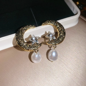 Macro detail of crescent moon and star earrings with vine relief and pearl drop