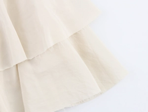 Close-up of beige tiered skirt fabric showing textured weave and decorative raw edges