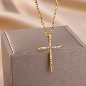 Close-up of a gold cross necklace with pavé cubic zirconia on a luxury jewelry box