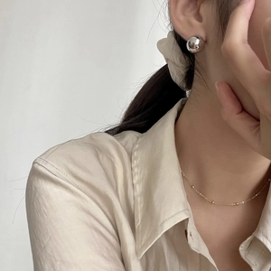 Close-up of minimalist S925 sterling silver spherical stud earrings worn by a model