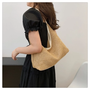 Side view of a large woven tote bag worn by a model in a minimalist indoor setting
