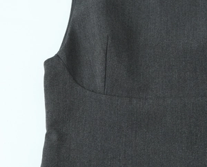 Close-up of dark grey woven fabric showing detailed stitching and chest darts on a dress