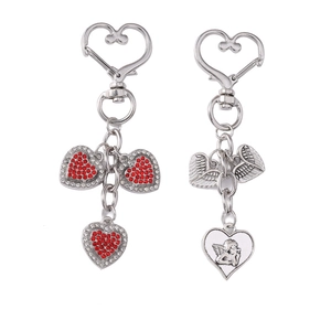 Silver angel wing heart keychains with sparkling red rhinestones on a white background