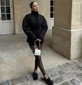 Street style shot of a black V-neck blazer with puff sleeves and a white quilted bag