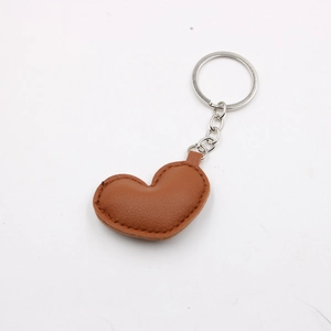 Close-up of brown PU leather heart keychain with metallic ring and detailed stitching