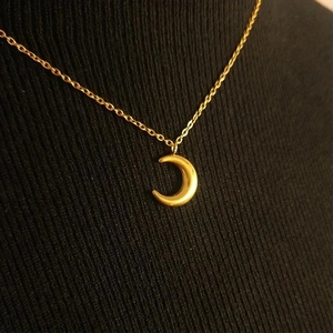 Elegant gold titanium steel crescent moon pendant necklace worn on a black knit top