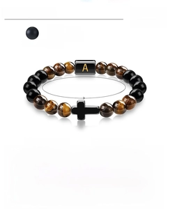 Macro detail of 8mm tiger eye bead bracelet with golden A letter and cross charm
