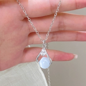 Detailed close-up of a silver necklace with sparkling stones and light blue bead