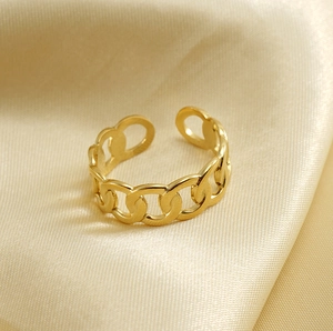 Macro shot of 18k gold plated Cuban link open ring on luxury champagne satin background