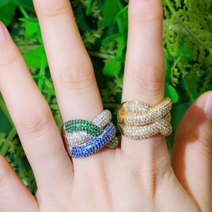 Eleganti anelli placcati oro e argento con zirconi presentati su una mano con verde
