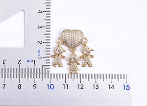 Dettaglio ciondolo a cuore placcato oro 18k con tre figure e scala graduata del righello