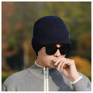 Detail of navy blue knitted beanie with short brim on male model in autumn setting