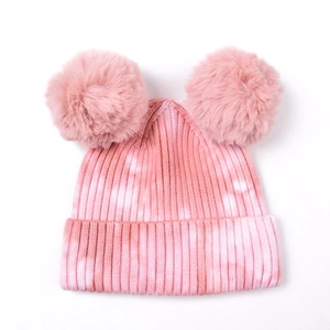 Dettaglio del cappello in maglia tie-dye rosa e bianco con due pompon in ecopelliccia