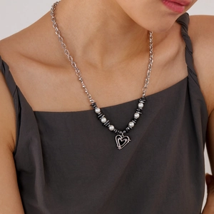Fashionable heart pendant necklace with white pearls and dark grey beads on a model