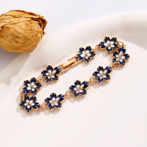 Detailed shot of retro gold bracelet with navy blue and white enamel flowers in a tray
