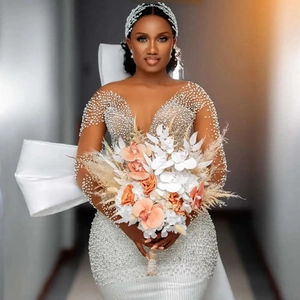 Robe de mariée sirène ornée de perles avec manches longues et grand nœud au dos