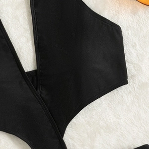Monokini noir licou ajouré avec franges sur fond de tapis en fausse fourrure blanche