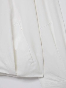 Detailed close-up of white linen bomber jacket showing fabric texture and pocket stitching