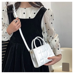 Détail du sac carré blanc avec motifs de cœur en relief 3D et petite poignée supérieure