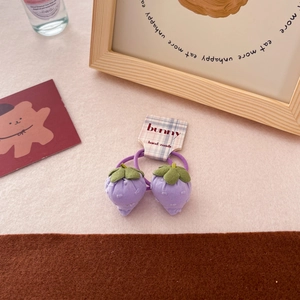 Detail of purple fabric strawberry hair tie with green leaves on a branded card