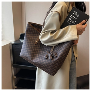 Detail of brown monogram tote bag with elephant charm and textured leather finish
