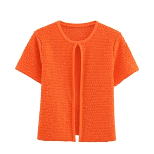 Detail der hellen orangefarbenen Strickjacke mit Pailletten und schimmernder Textur