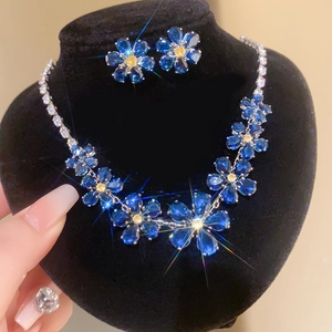 Détail du parure collier et boucles d'oreilles fleurs bleues sur support en velours
