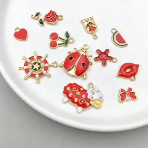 Flat lay of red and gold enamel charms including cherry and strawberry for DIY jewelry making