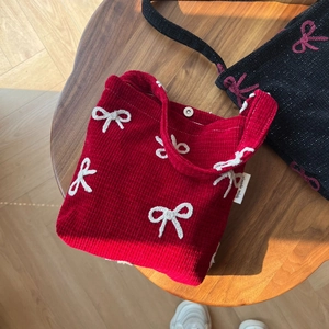 Détail du sac cabas en velours côtelé rouge avec nœud brodé blanc et fermoir aimanté