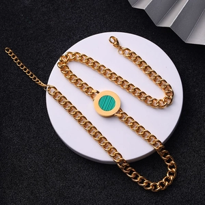 Detail of gold chain necklace featuring a green malachite round pendant and lobster clasp