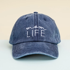 Detailed view of mom LIFE white embroidery on washed navy blue cotton baseball cap texture