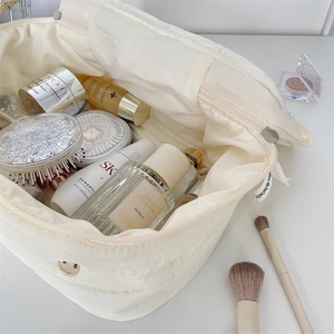 Close-up of quilted cream makeup bag showing spacious interior and soft fabric texture