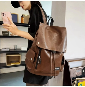 Dettaglio zaino in pelle marrone con chiusura a coulisse e tasche laterali