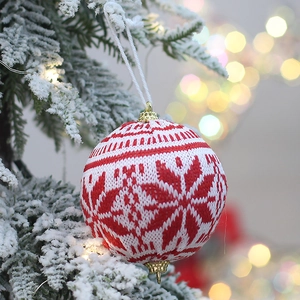 Knitted Christmas tree ornament with snowflake pattern hanging on a snowy branch