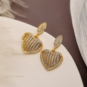 Luxurious gold-plated heart drop earrings with stripes and crystals on ivory podium
