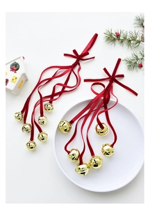 Detailed view of golden Christmas bells with long red velvet ribbons on festive table