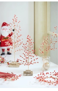 Close-up of red acrylic Christmas tree branches with festive beads and glitter base