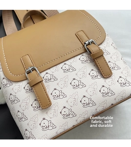 Détail du rabat en cuir marron avec boucles et motif d'ours sur le sac à dos décontracté