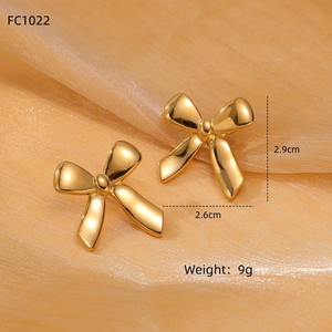 Elegant gold bow-shaped titanium steel earrings on champagne silk background 2.9cm 9g