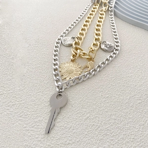 Détail d'un collier hip-hop multicouche avec pendentifs clé, tournesol et lune stylisés