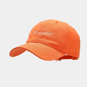 Detail of white OK AND? embroidery on the front of the orange cotton baseball cap