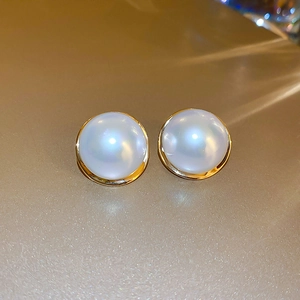 Macro shot of French vintage faux pearl earrings with golden circular metallic frames