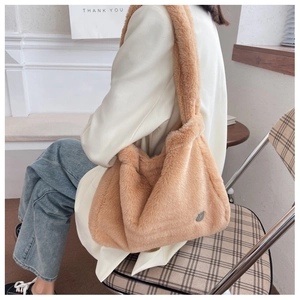 Detail view of a fluffy light brown plush tote bag showing soft fur texture and metal badge