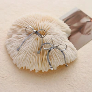 Detail of silver bow earrings with a unique woven metal mesh texture and minimalist design