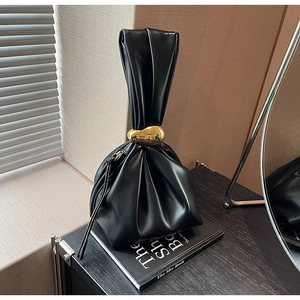 Macro view of black pleated leather bucket bag with a decorative gold metal ring
