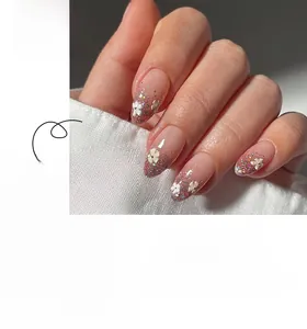 Detail of pink glitter gradient almond nails with white 3D floral accents and glossy finish
