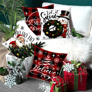 Set of 4 Christmas pillow covers with red plaid and festive motifs on a cozy white sofa