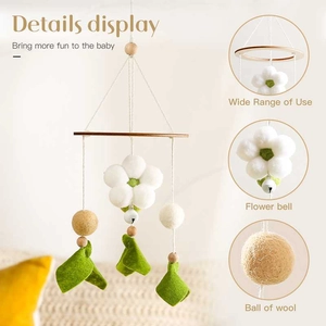 Close-up of wool felt flowers and bells on a wooden baby mobile for nursery decor