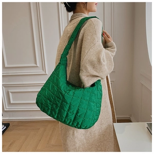 Detail of green quilted puffer shoulder bag in soft nylon shown from a side view angle